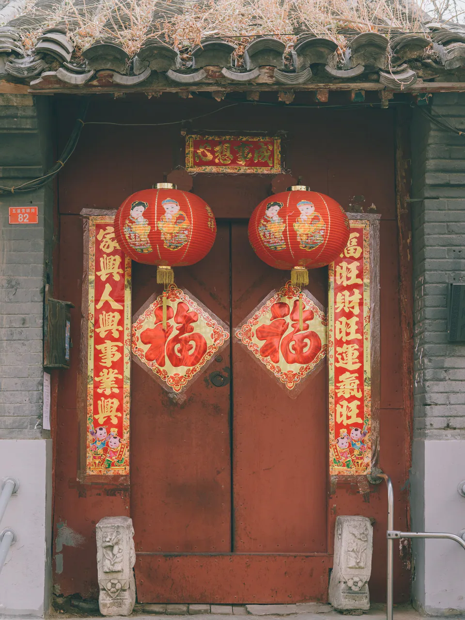 Červené lampióny a novoročné nápisy na tradičných dverách v Pekingu