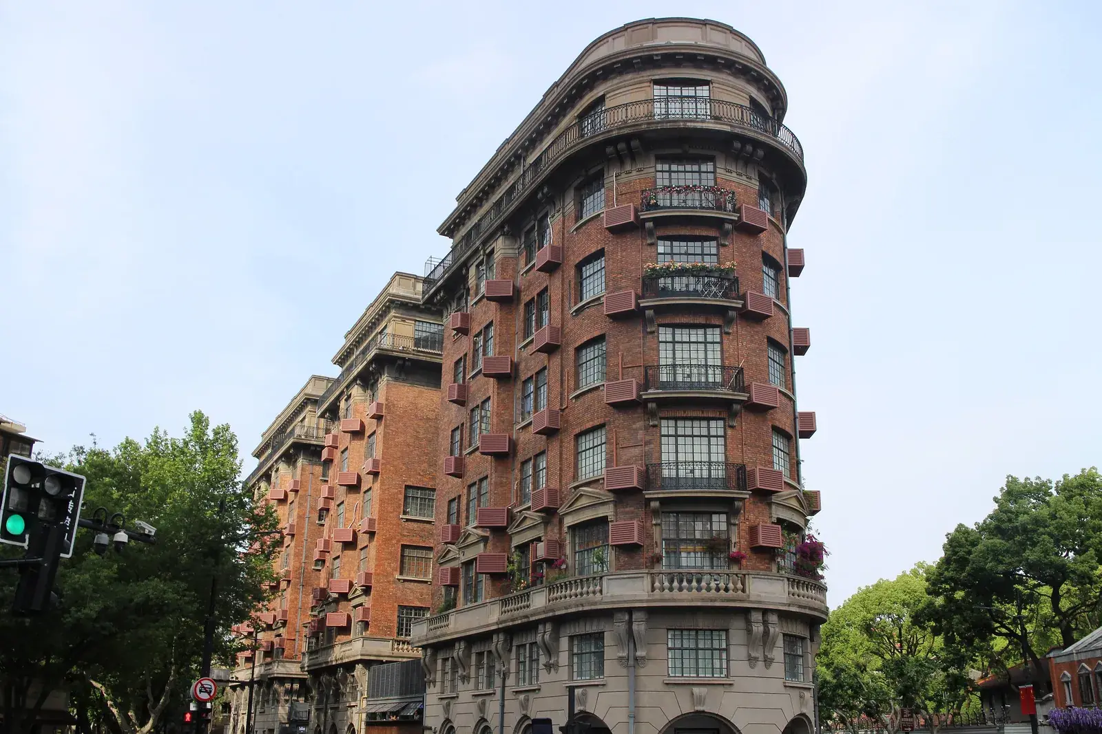 Tehlová budova Wukang Mansion v tvare lode na rohu ulice v Šanghaji